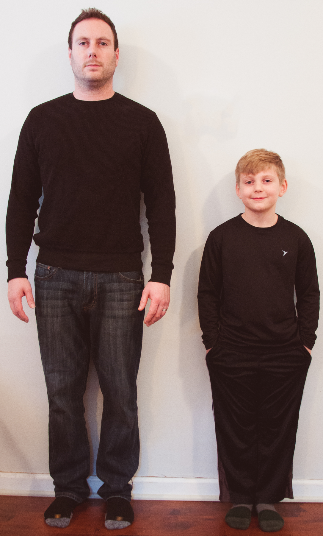 A picture of a man and boy standing next to each other. The top of the boy's head comes up to the chest of the man.