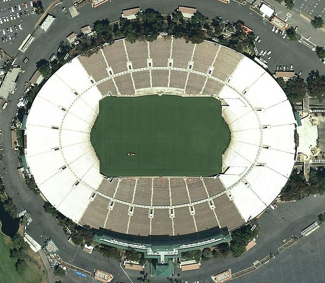A satellite image looking down on a stadium in the shape of an oval. The stadium is slightly wider than it is tall. 